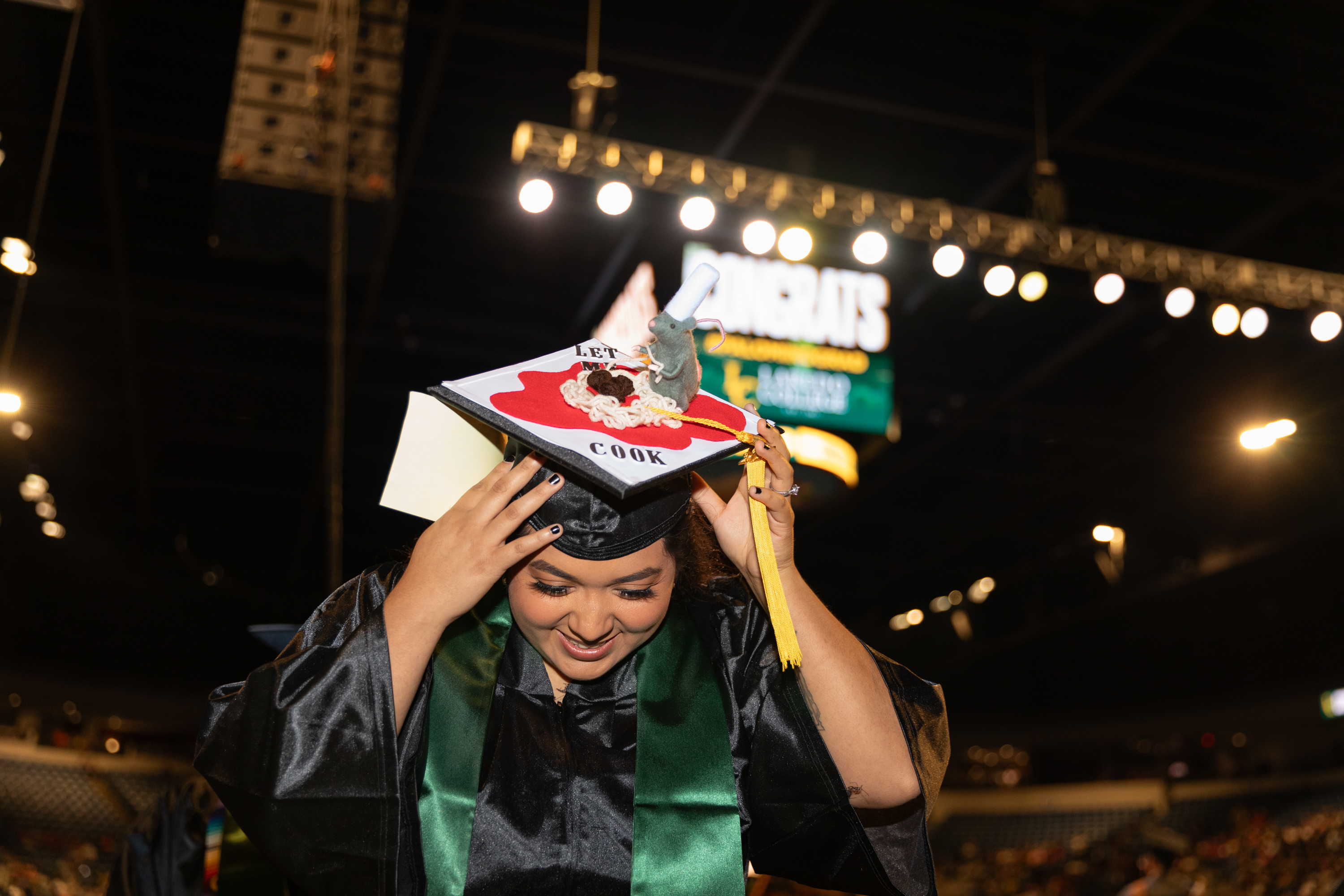 Student adjusts cap during graduation ceremony